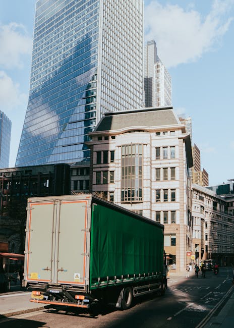 A view of the River Thames in London with modern high-rise buildings and partially constructed skyscrapers in the background. In the foreground, yellow and red floating barriers are positioned along the riverbank, indicating a loading or unloading area. The scene is taken during daylight with partly cloudy skies, and the water reflects the urban skyline. This urban environment highlights the need for efficient home relocation and furniture transport services, like those offered by Man With a Van Vauxhall, which manage packing, loading, and transporting household items during house removals in the city.